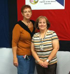 Holbrook Public Library Officers: Two women standing side by side in front of a wall with a red, black, and white banner.